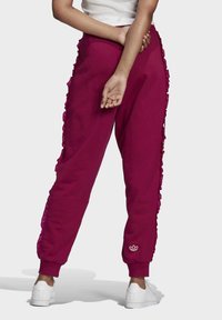 Fuchsieové tepláky s volánovými bočními detaily, vyrobené z měkké látky. Mají elastický pas a malé logo na kotníku.