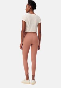 Lichte beige cropped t-shirt gecombineerd met aansluitende, blush roze leggings. De leggings hebben een hoge taille en een gladde textuur.