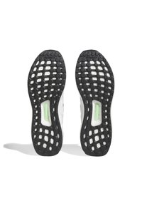 Black rubber sneaker soles with circular tread pattern; white midsole with a green accent; lightweight and flexible design.
