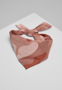 En rosa og terrakotta mønstret scarf laget av mykt stoff, bundet i trekantform med en løs knute i midten.