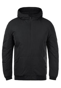 Veste noire à capuche, zip sur le devant, deux poches latérales, poignets et ourlet côtelés, design rembourré, texture lisse, style minimaliste.