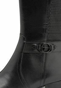 Fekete bőrből készült boka csizma, texturált hálós panellel, kör alakú csattal és karcsú, kúpos siluettel.