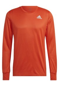 T-shirt de sport à manches longues en orange vif, fabriqué en tissu léger et texturé. Il présente un col rond et un logo adidas blanc sur la poitrine.