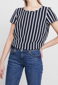 Marineblauw en witte gestreepte korte mouwen top met een ronde hals; gecombineerd met blauwe jeans, met een ontspannen pasvorm en een soepele stoftextuur.