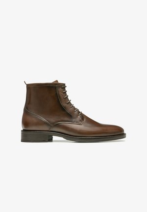 Bottines en cuir marron avec une finition lisse, bout rond et un laçage à cinq œillets. Présente une languette au talon et un talon bas empilé.