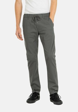 Pantalones grises ligeros con cintura elástica y cordón ajustable; bolsillos laterales; corte slim; combinados con zapatillas negras.