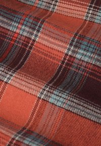 Geruite stof in tinten oranje, rood en blauw met een zachte textuur; bevat elkaar kruisende lijnen van verschillende diktes.