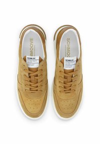 Baskets en daim beige avec des détails perforés, bout rond, lacets plats et semelle en caoutchouc blanche. Les étiquettes à l'intérieur indiquent la marque et les informations d'entretien.