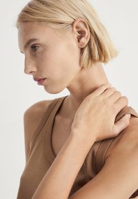 Bruine mouwloze top van zacht materiaal, met een ronde halslijn en een getailleerd ontwerp, gekenmerkt door een gladde textuur en minimale stiksels.