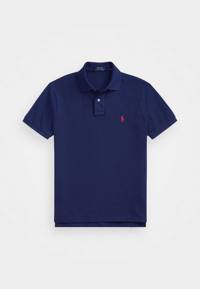 Polo de cor azul marinho com colarinho clássico, mangas curtas e um logo bordado vermelho no lado esquerdo do peito. Fabricado em material de algodão suave.
