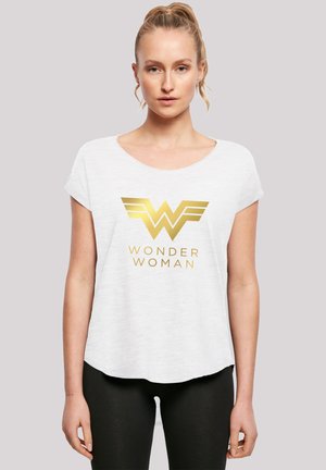 Valge lühikeste varrukatega T-särk ümmarguse kaelusega ja siledast materjalist, mille esiküljel on kuldne "Wonder Woman" logo ja tiiva aktsent.