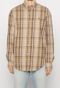 Camicia a quadri marrone e beige con maniche lunghe, dotata di colletto e un piccolo logo ricamato sul petto.