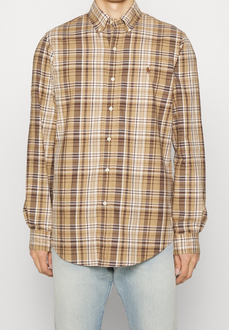Camicia a quadri marrone e beige con maniche lunghe, dotata di colletto e un piccolo logo ricamato sul petto.