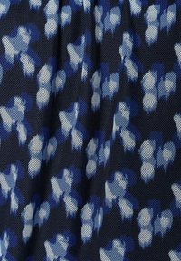 Marineblauer Stoff mit einem strukturierten Mesh-Design, verziert mit hellblauen und weißen abstrakten Mustern.