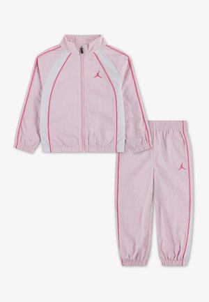Ensemble de survêtement deux-pièces rose clair avec panneaux blancs et bordures roses, comprenant une veste zippée et un pantalon à poignets élastiques avec un petit logo sur la poitrine et la cuisse.