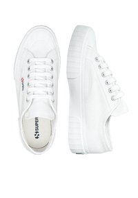 Vita kanvas sneakers med en texturerad ovandel, rund tå och en tjock gummisula, med silverögon och "SUPERGA"-logotyp.