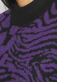 Lila und schwarzer Pullover mit einem strukturierten Stoff und einem zebra gestreiften Muster, geripptem Ausschnitt und weicher, gewebter Optik.
