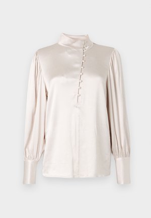 Jasno beżowa bluzka z długim rękawem, z wysokim kołnierzem, z zapięciem na guziki na przodzie oraz bufiastymi rękawami z dopasowanymi mankietami. Gładka tkanina.