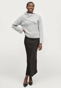 Grauer gestrickter Pullover mit asymmetrischem Kragen, kombiniert mit einem schwarzen satin Maxi-Rock und schwarzen spitzen High Heels.