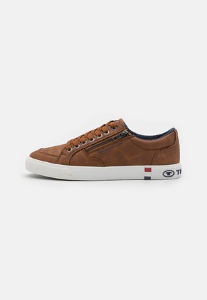 Baskets en cuir marron avec semelle en caoutchouc blanche, à lacets à l'avant, fermeture éclair sur le côté, et accents de logo en rouge, blanc et bleu au niveau du talon.