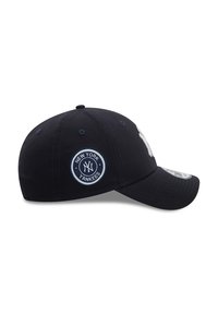 Marineblå baseballcaps med en hvit brodert "NY" logo og sirkulær "New York Yankees" patch. Laget av bomull med en buet skjerm.