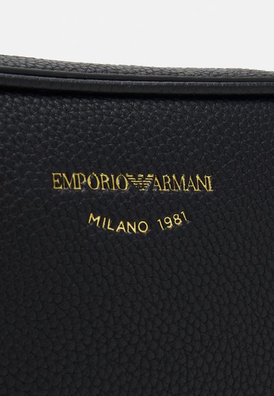 Sac en cuir noir texturé avec un logo doré en relief "EMPORIO ARMANI" et "MILANO 1981" sur la surface.