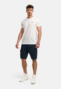 Hvid bomulds t-shirt med et lille grafisk design, parret med marineblå cargo shorts med lommer og hvide høj-top sneakers.