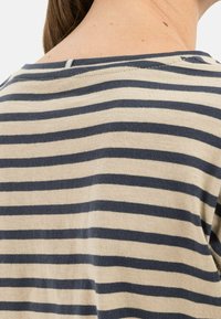 Striped cotton top with navy and beige horizontal stripes, featuring a boat neckline and a small back closure. Soft, lightweight texture.
