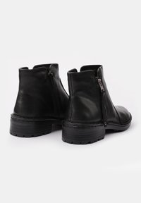 Stivaletti neri in pelle con punta tonda, cerniere laterali, texture liscia e suola in gomma robusta con un leggero tacco.