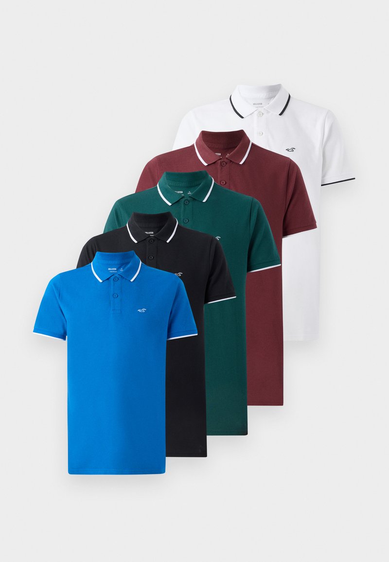 Cinq polos en bleu, noir, vert, bourgogne et blanc. Fabriqués en coton, avec une patte de boutonnage à deux boutons et des finitions de col contrastantes.