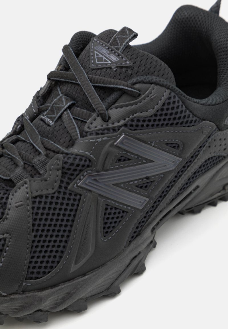 Schwarzer Sportschuh aus Mesh-Material, mit elegantem Design, strukturierten Oberflächen und ausgeprägter Gummisohle mit multidirektionalen Stollen.