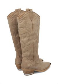 Botas de vaquero de ante beige con detalles de costura, punteras afiladas y tacones apilados. Cuentan con pestañas de tiro para facilitar su uso.