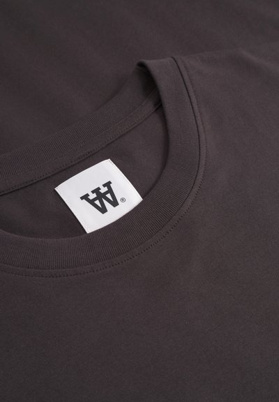 Diepgrijze katoenen t-shirt met een ronde hals, voorzien van een wit etiket met een zwart logo. Stijlvolle textuur en een schoon ontwerp.