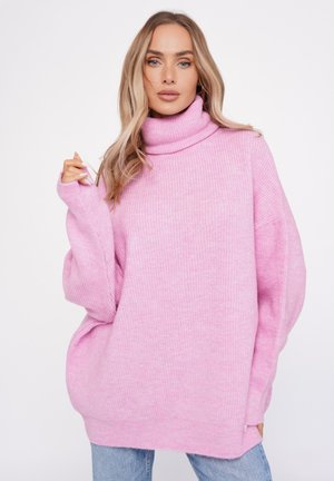 Przeszłe różowa sweter o oversize'owym kroju z wysokim kołnierzem typu golf, prążkowaną teksturą i opadającymi ramionami. Posiada boczne rozcięcia dla dodatkowego komfortu.