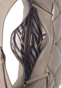 Beige læderhåndtaske med en quiltet overflade, der viser en åben lynlås, som afslører en stribet stofforing i nuancer af creme og mørk lilla.