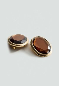 Gouden oorbellen met grote, facetteerde bruine edelstenen in een ovale vorm met zachte randen en glanzende oppervlakken.