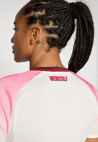 White athletic shirt with pink gradient sleeves. Features "WERKSELF" logo in red on the back, and textured fabric.