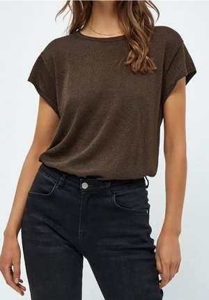 Bruin shirt met korte mouwen van een zachte, gestructureerde stof met een subtiele glans, gecombineerd met een donkere spijkerbroek met voorzakken en metalen knoop.