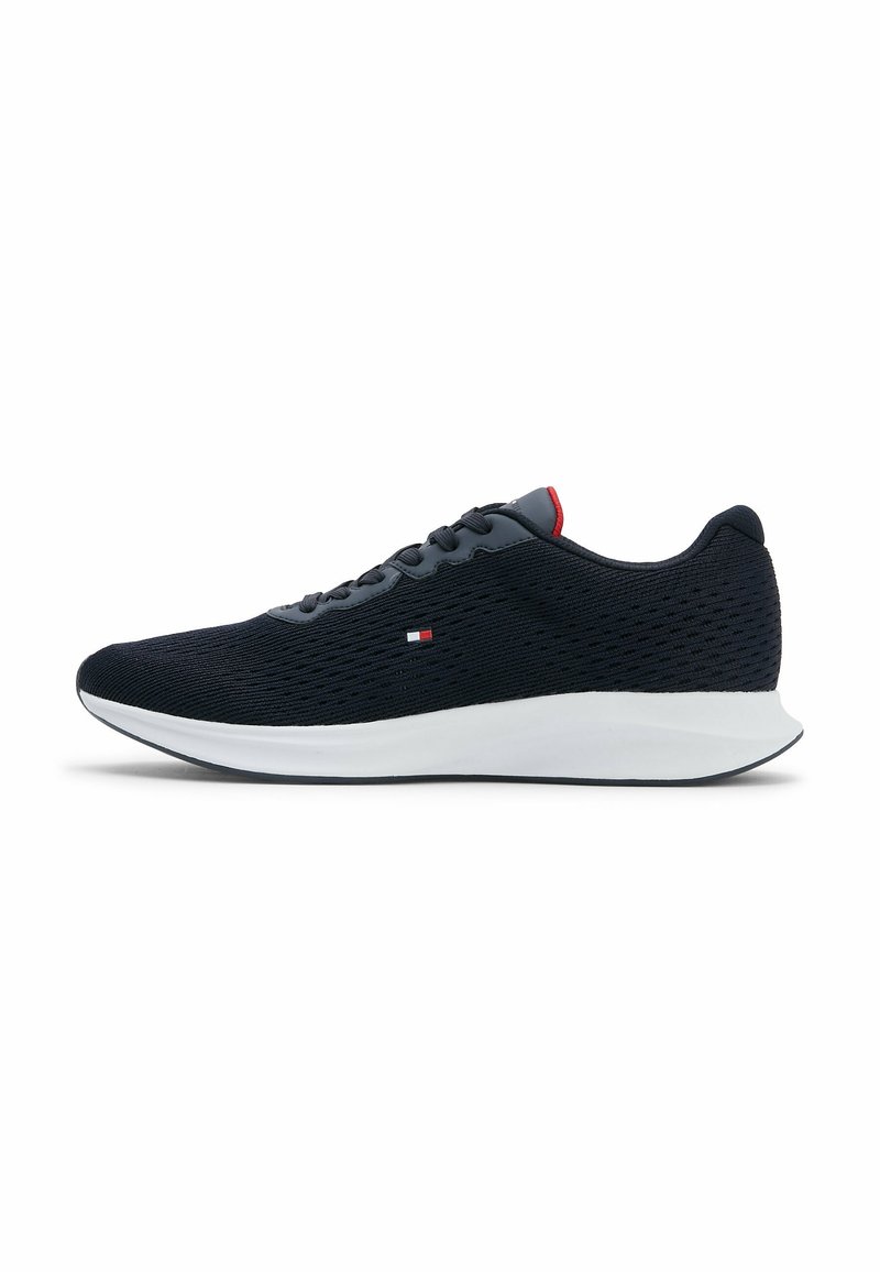 Chaussure de course en mesh noir avec semelle blanche, lacets noirs, petit logo rouge et blanc sur le côté, et accent rouge sur la languette.