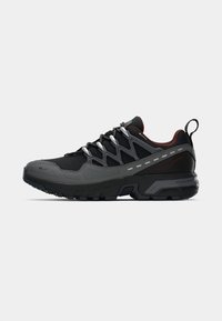 Black and gray athletic shoe with textured mesh and synthetic upper, reflective accents, thick rubber sole, and supportive heel counter.