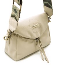 Bolso bandolera de cuero color crema con tapa redondeada, herrajes plateados, cierre de cremallera y correa ajustable con un diseño estampado.