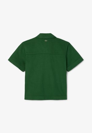 Camicia verde a maniche corte con colletto, chiusura a bottoni e yoke posteriore. Presenta un piccolo logo sopra lo yoke. Realizzata in un tessuto leggero.