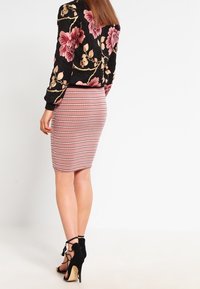 Černá bomber bunda s květinovým vzorem růžových a krémových květin, doplněná o přiléhavou růžovou pruhovanou sukni a černé sandály na vysokém podpatku se stahovacími pásky.