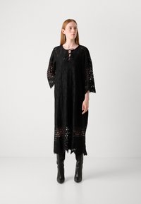 Black lace dress featuring a wide cut, three-quarter sleeves, a keyhole neckline, and an intricate hem with cutout patterns.