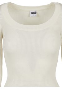 Pull en maille côtelée de couleur crème avec col rond, manches longues et étiquette "Urban Classics" taille XS à l'intérieur du col.