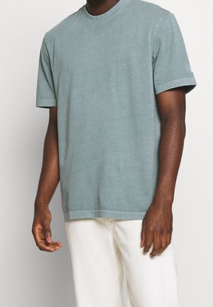 T-shirt en coton vert clair à manches courtes, col rond, coupe décontractée, avec une texture subtile et des ourlets cousus.