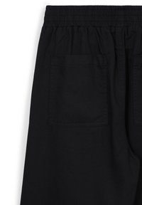 Pantalons noirs avec taille élastique et une seule poche arrière visible sur le côté droit.