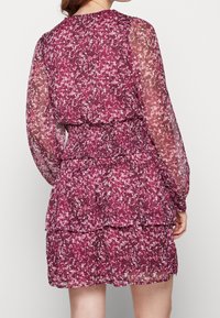 Minišaty s květinovým vzorem z průsvitné, lehké tkaniny s nařaseným pasem a dlouhými rukávy. Hlavní barva: tmavě růžová s bílými akcenty.
