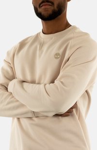 Felpa beige con polsini e scollatura a costine, caratterizzata da un logo in rilievo sul petto. Texture del tessuto morbida, design a collo tondo.