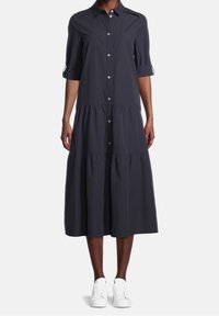 Granatowa sukienka koszulowa o warstwowym fasonie, z rękawami do łokcia oraz luźnym krojem, zestawiona z białymi sneakersami.